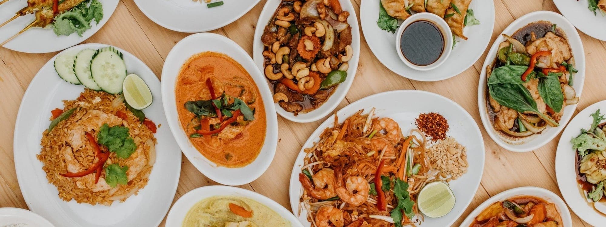 Overhead spread of colourful Thai dishes including curries, fried rice, pad thai and salads at Sri Non Thai Street Food