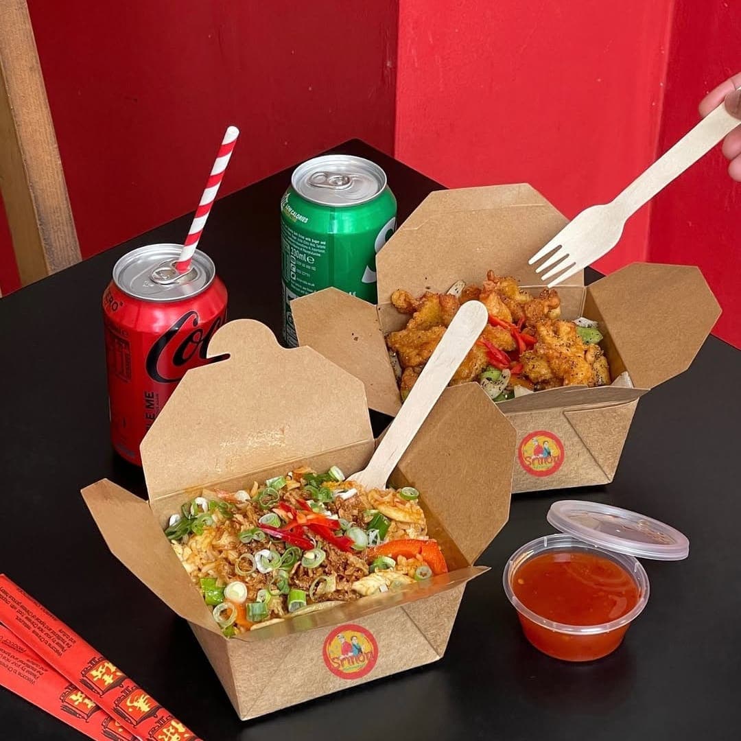 Sri Non Thai Street Food lunch boxes with pad thai and fried chicken on a black table with drinks