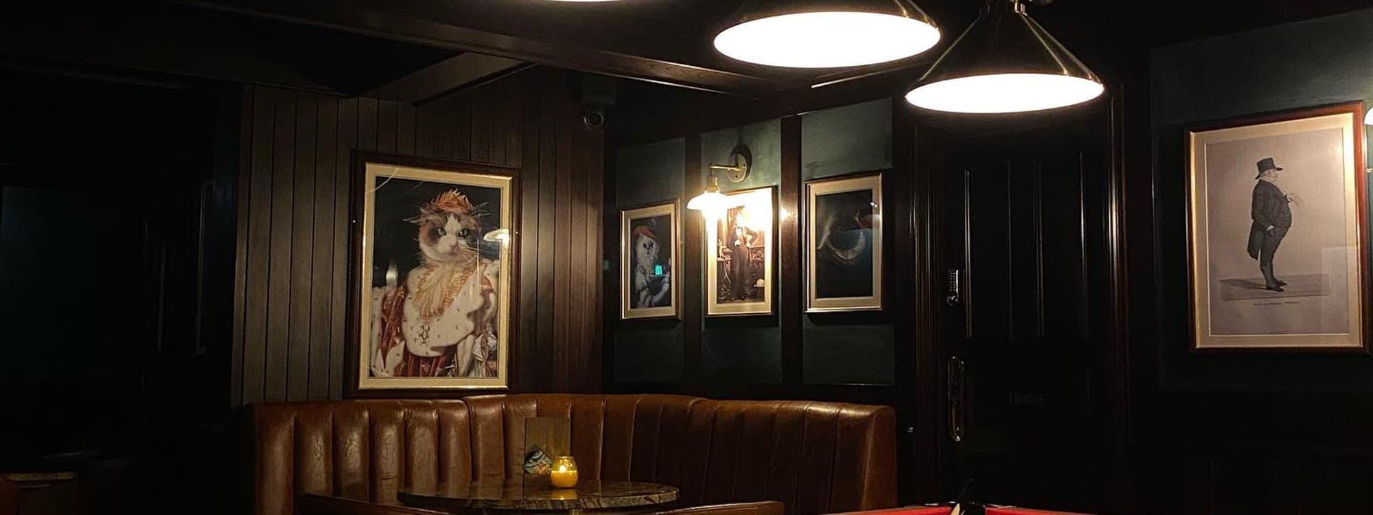 The Bankers Cat curved mahogany bar with white cask handpumps and amber chandelier lighting
