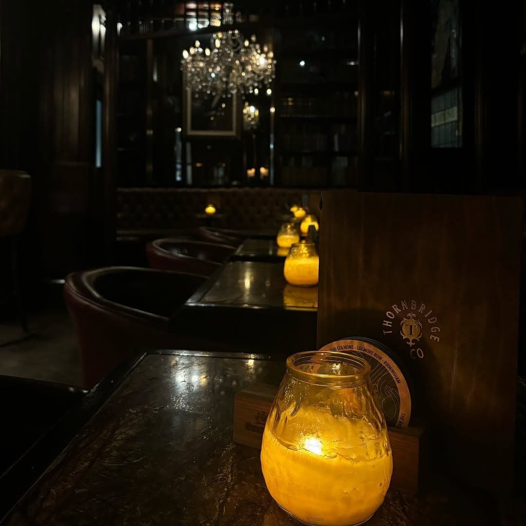 The Bankers Cat tealight candles on dark tables with chandelier visible in distance