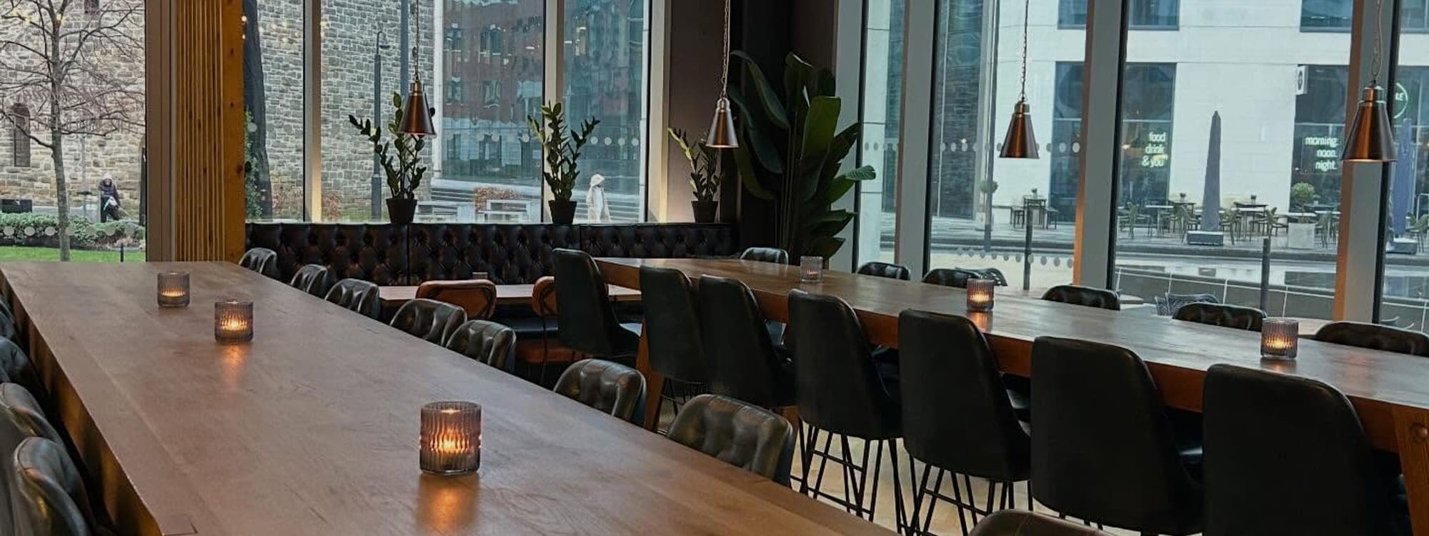The Good Luck Club — spacious dining interior with industrial pendant lights and long wooden table