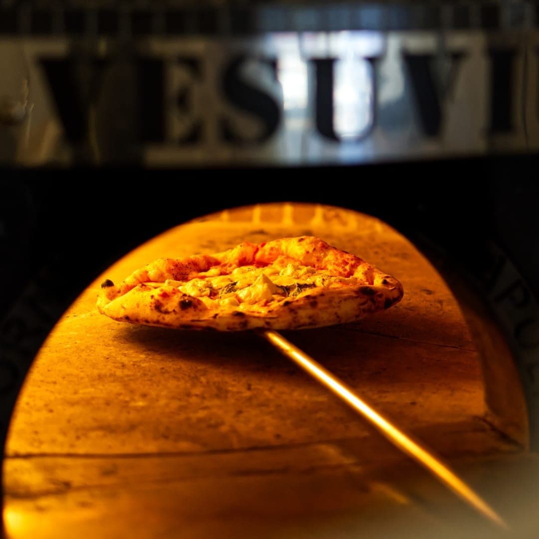VESUVIUS — Margherita pizza inside a glowing wood-fired oven with Vesuvius sign above