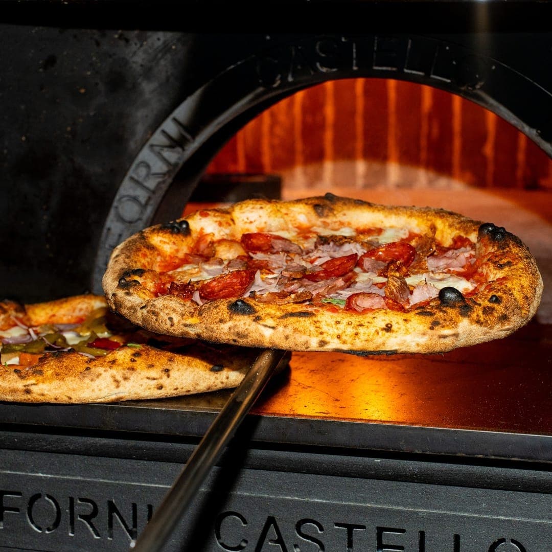 VESUVIUS — pizza being pulled from the Forno Castello wood-fired oven