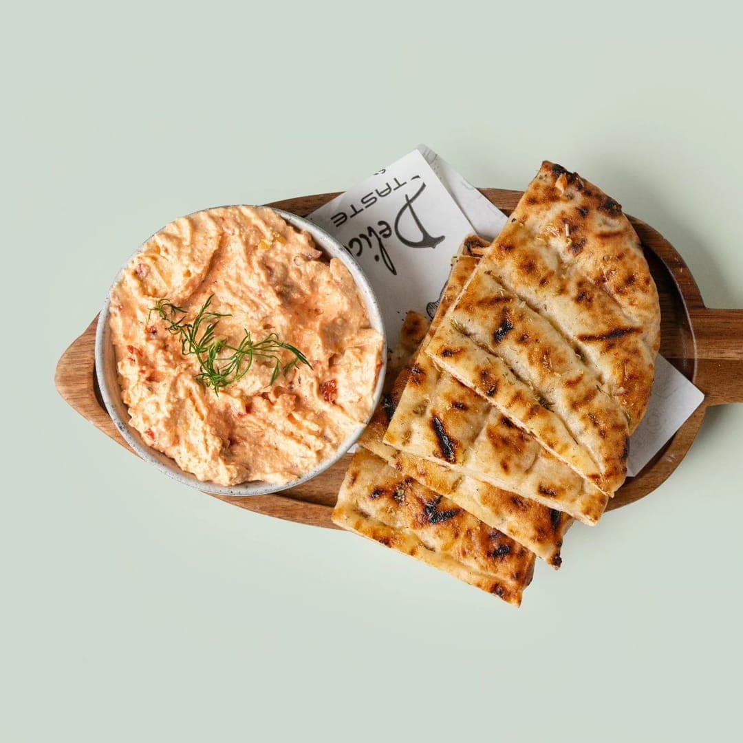 Tyrokafteri spiced cheese dip with chargrilled pitta bread on a wooden paddle board