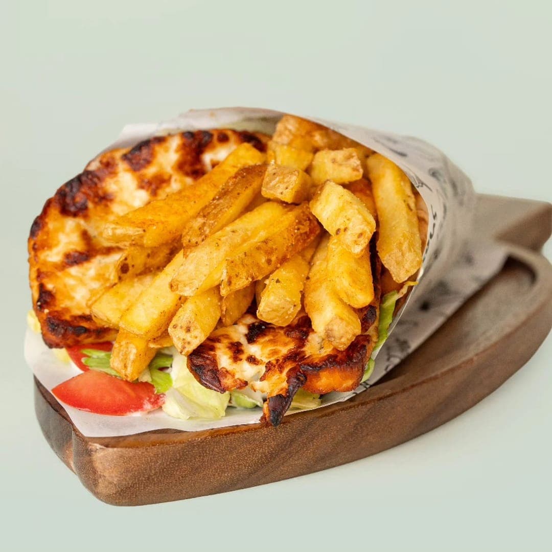 Gyros wrap in branded Yiros paper with skin-on fries on a wooden board