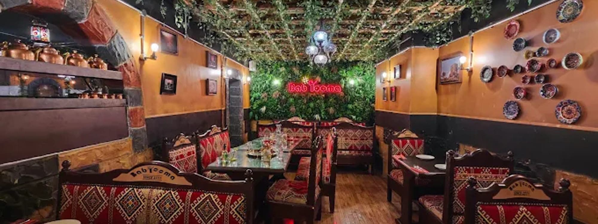 Bab Tooma Leeds — dining room interior with green vine ceiling, ornate seating and neon sign