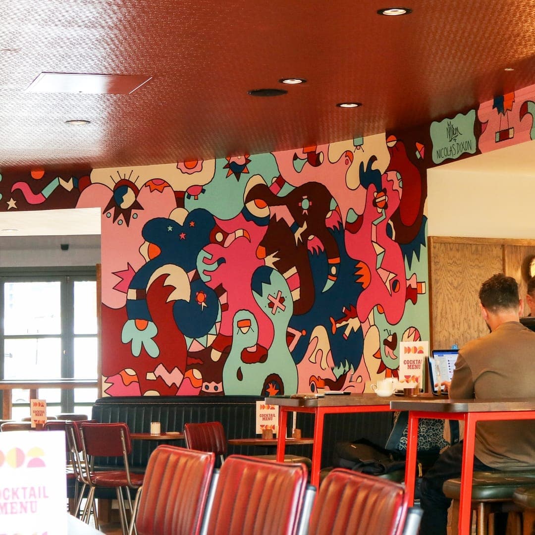 Interior of Brewery Wharf Tavern showing the dining room with colourful illustrated wall mural and bar counter