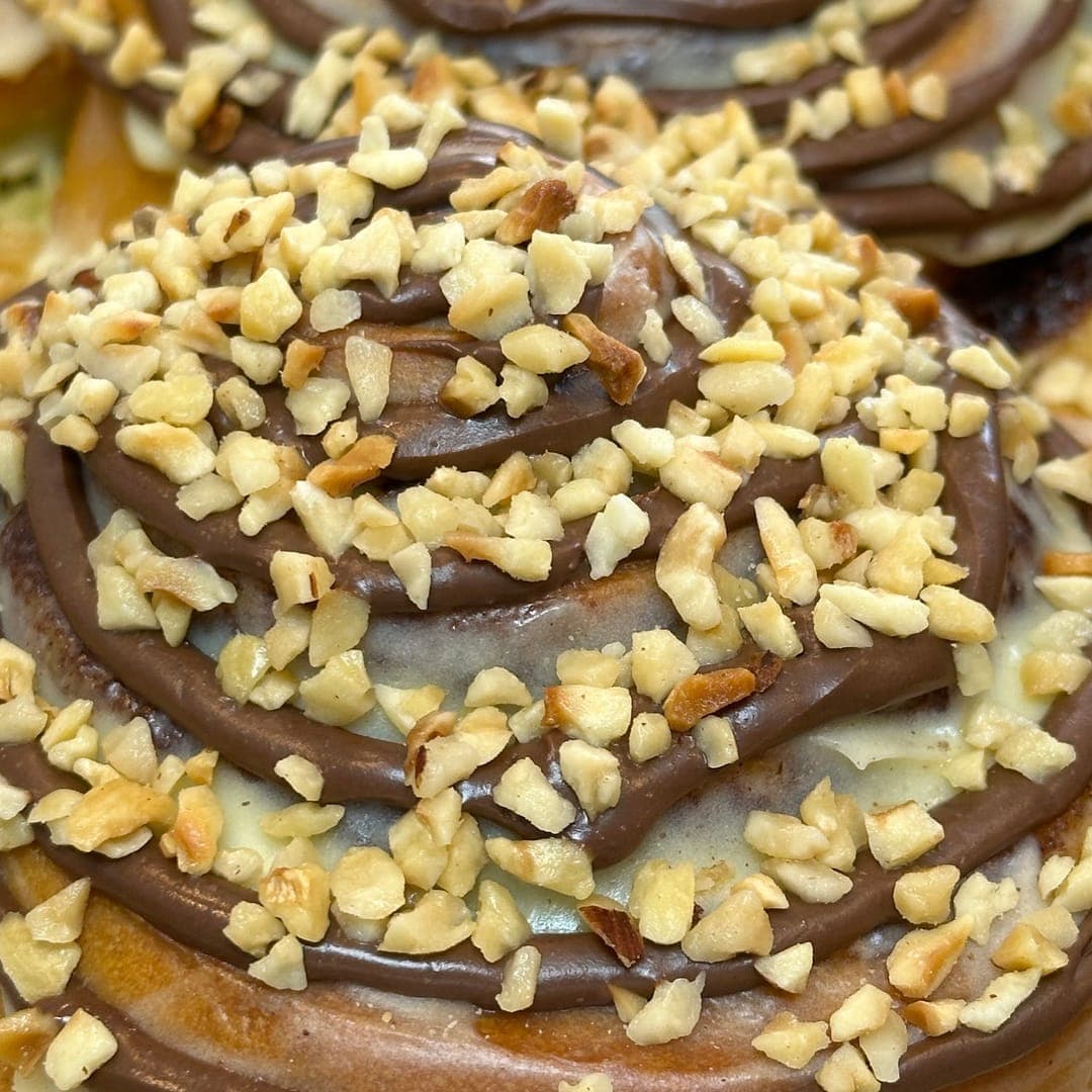 Close-up of Cinnaful cinnamon rolls covered in chocolate glaze and crushed hazelnuts