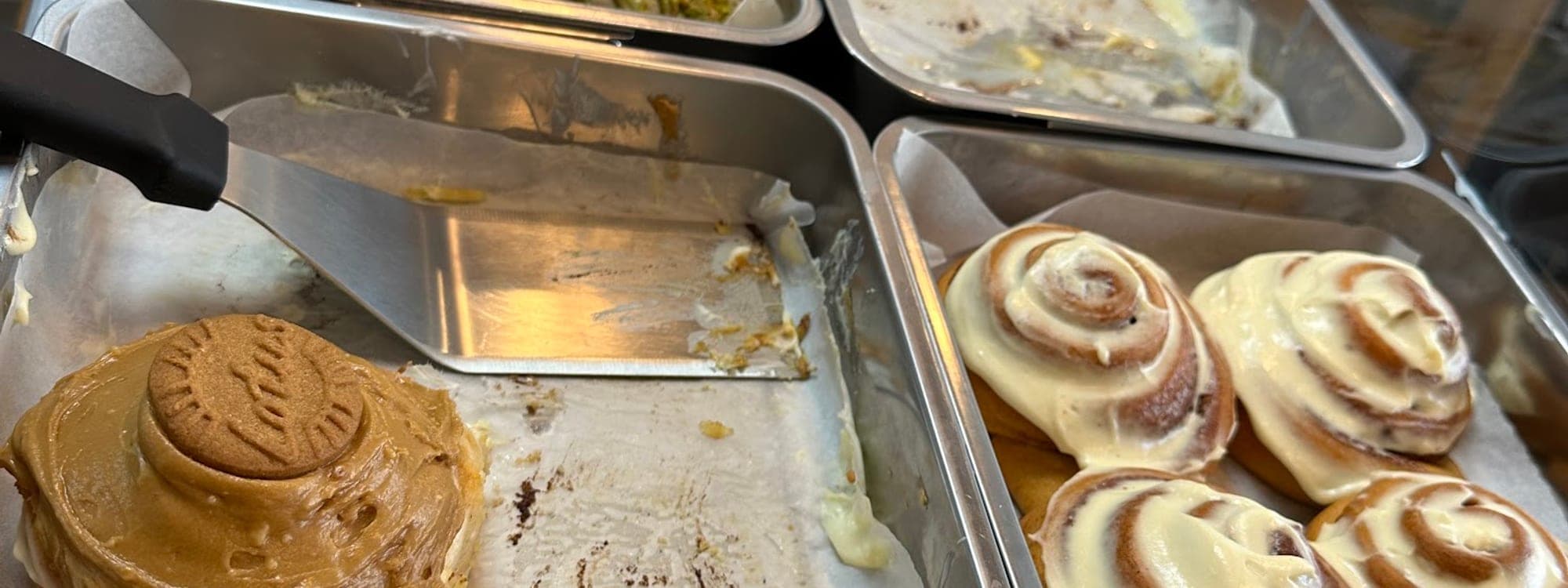 Display counter at Cinnaful Leeds showing trays of Lotus Biscoff, pistachio and cream cheese topped cinnamon rolls
