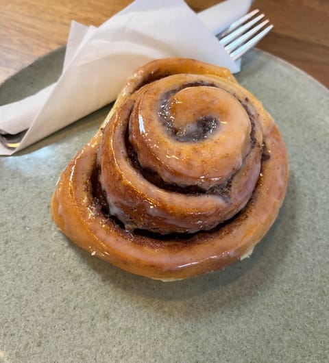 Classic glazed cinnamon roll on a sage green plate at Cinnaful Leeds