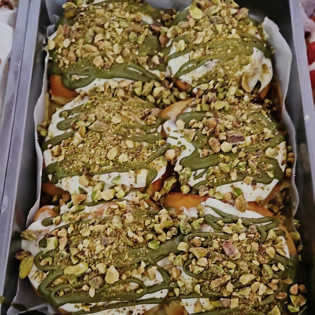 Tray of Cinnaful cinnamon rolls drizzled with matcha cream and topped with crushed pistachios