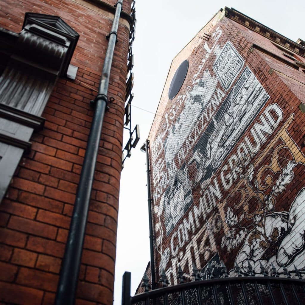 Common Ground mural by Mike Winnard at New York House, Harper Street, Leeds — "Common Ground" written in multiple Leeds languages with Kirkgate-themed iconography