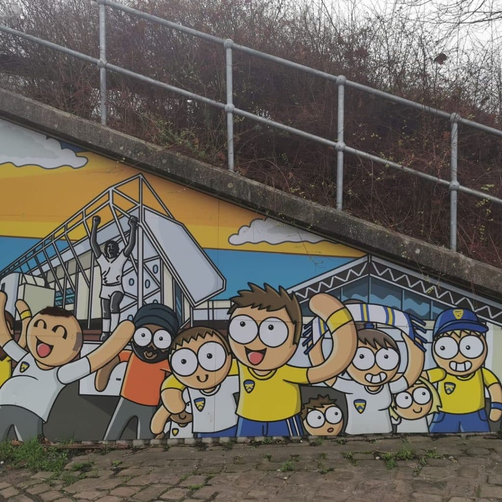 Fans Scene by Andy Sykes (Hexjibber) in the Holbeck Moor pedestrian subway, Leeds — cartoon Leeds United fans celebrating with stadium imagery