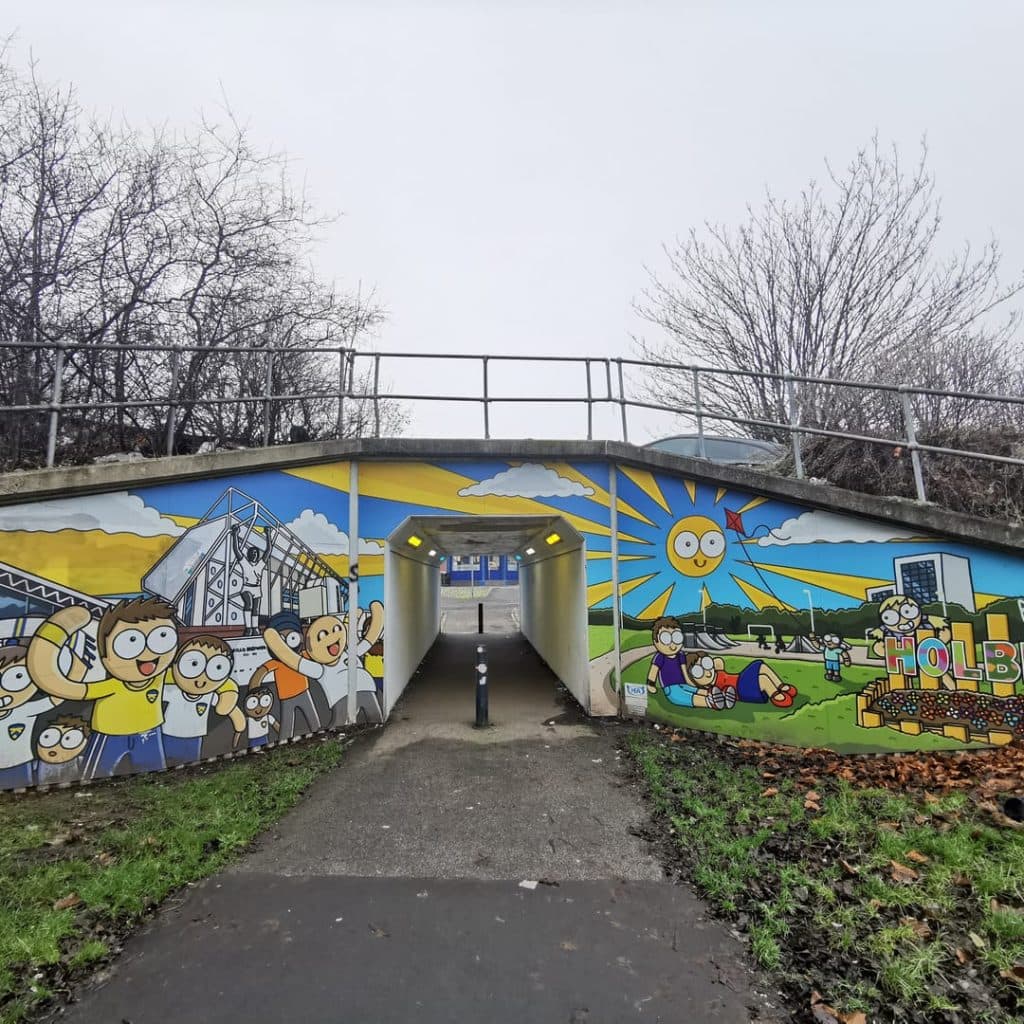 Fans Scene mural — wider view of the subway showing the painted boardings and Holbeck/Beck Park lettering