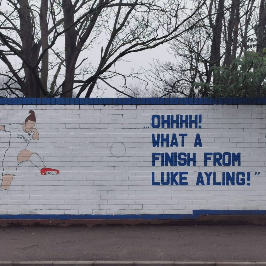 Last Game Before the World Stopped mural by Burley Banksy on Whitehall Road, Wortley, Leeds — Luke Ayling celebrating his goal with the commentary line painted alongside