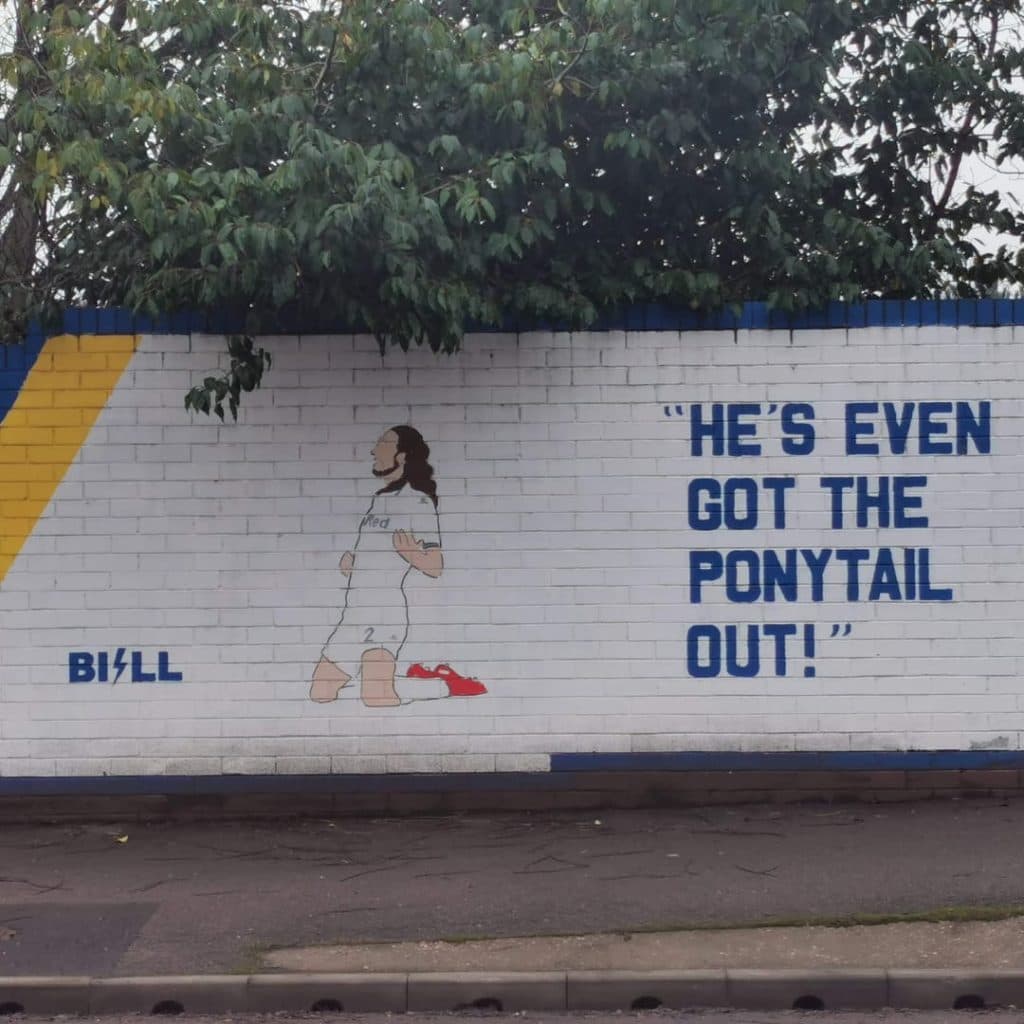 Companion panel showing the same Burley Banksy piece with the painted line "He's even got the ponytail out!"