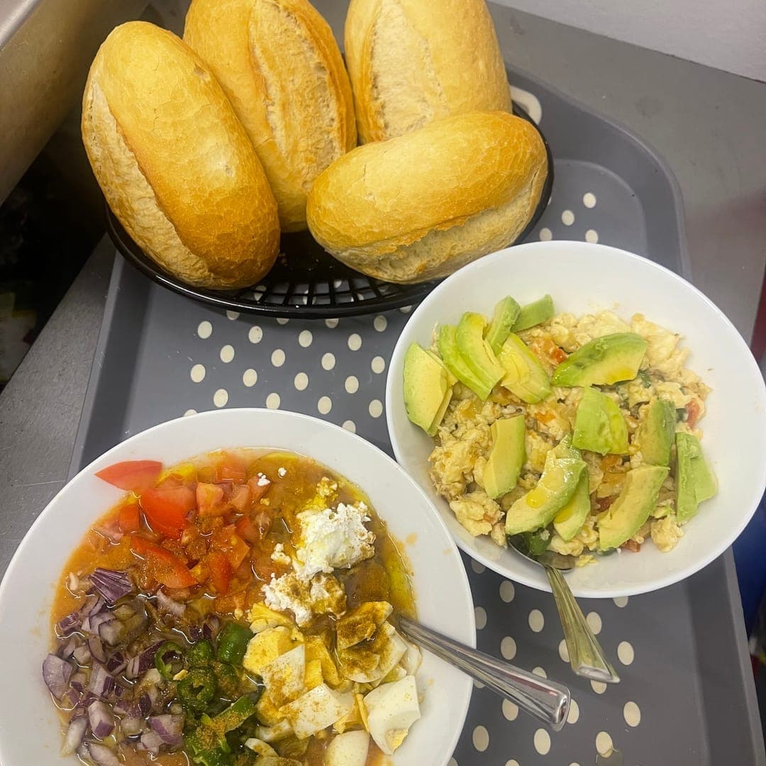 Shakshuka and avocado scramble breakfast dishes with bread rolls at Miracle cafe