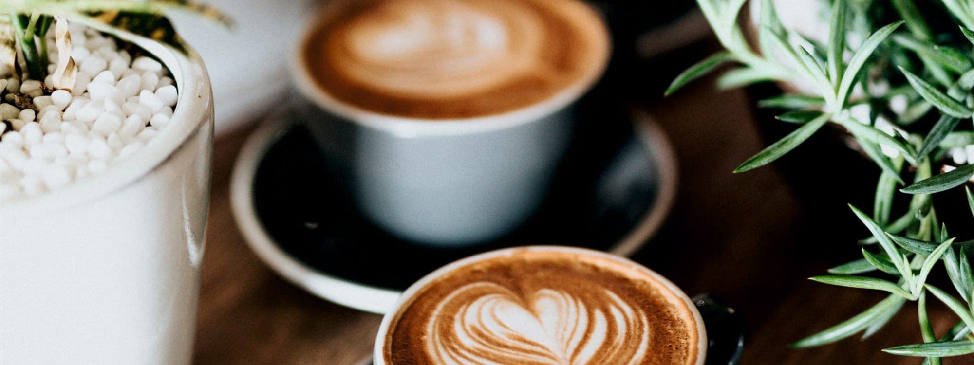 Two flat white coffees with heart-shaped latte art on a wooden table at Miracle cafe