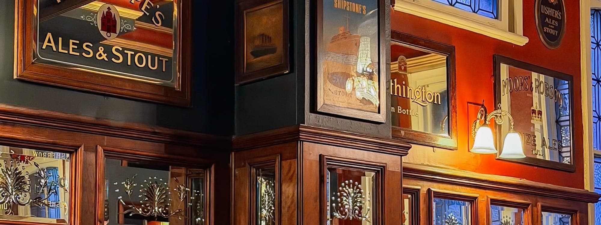 Victorian pub interior at The Victoria and Commercial with vintage brewery advertising signs on dark wood panelled walls and leather booth seating