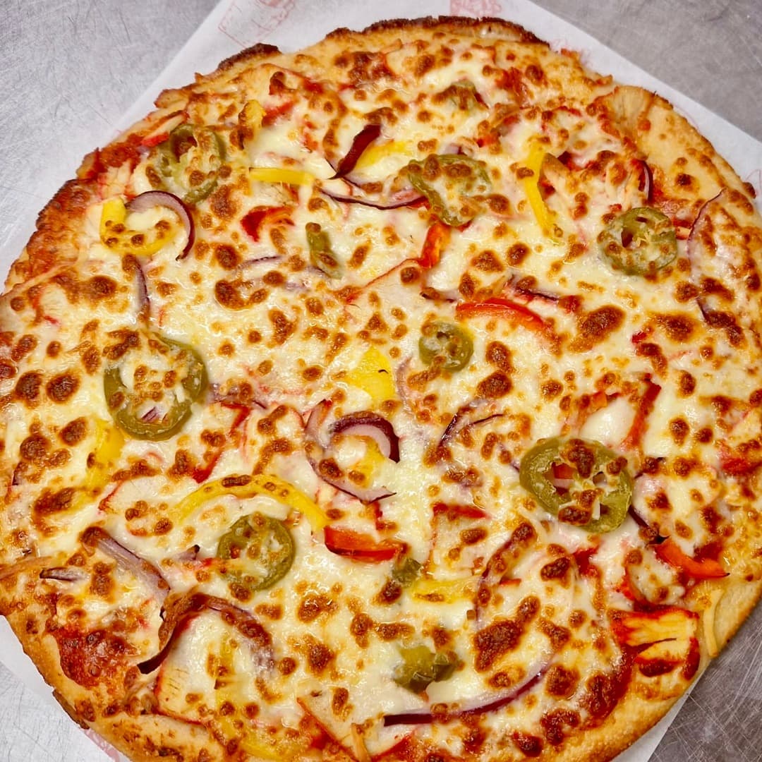 A pizza topped with melted cheese, sliced jalapeños, red onion and yellow and red peppers, on branded paper at Fatbros, Bramley, Leeds.