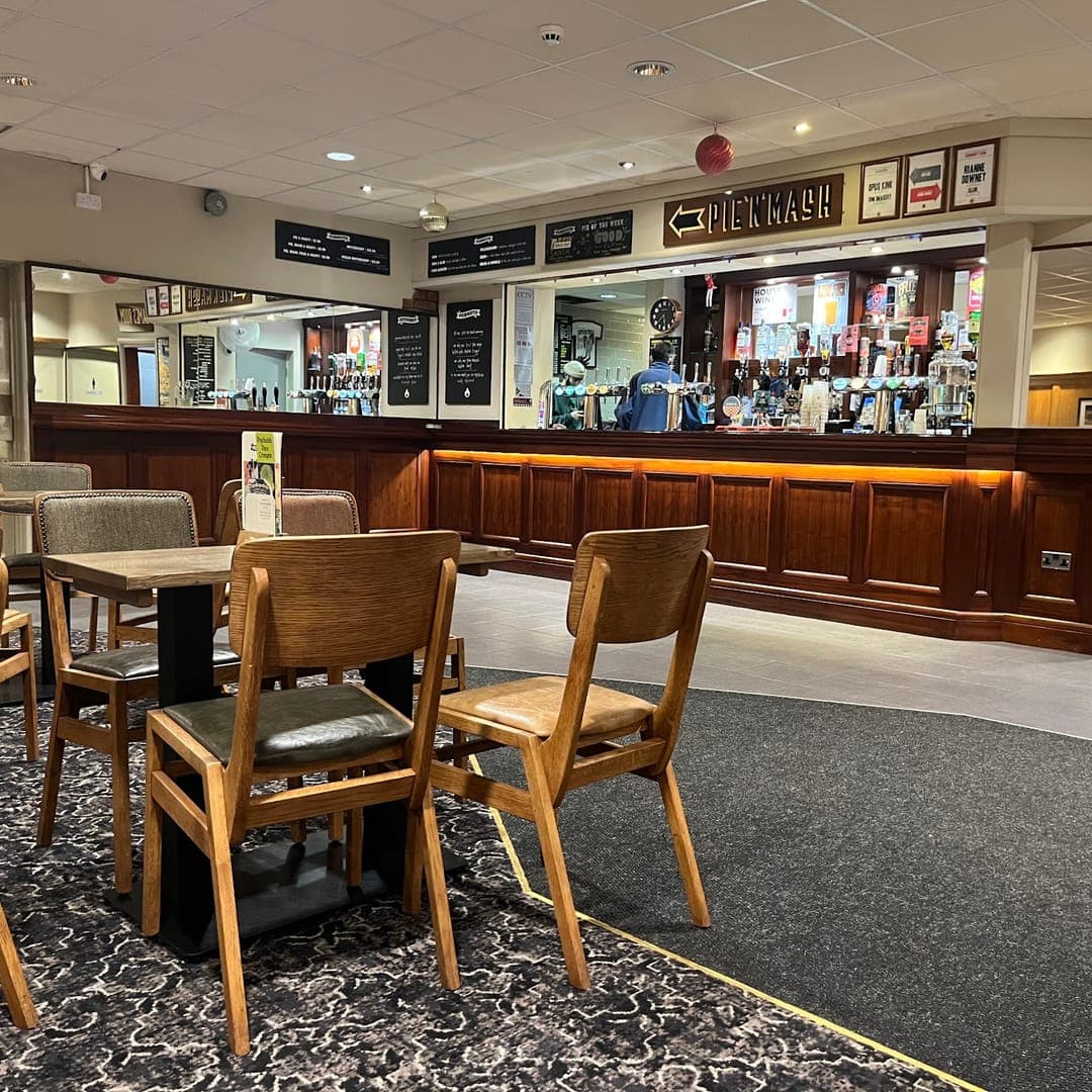 Wooden bar at Brudenell Social Club Leeds with cask taps, tables and Games Room sign on the back wall