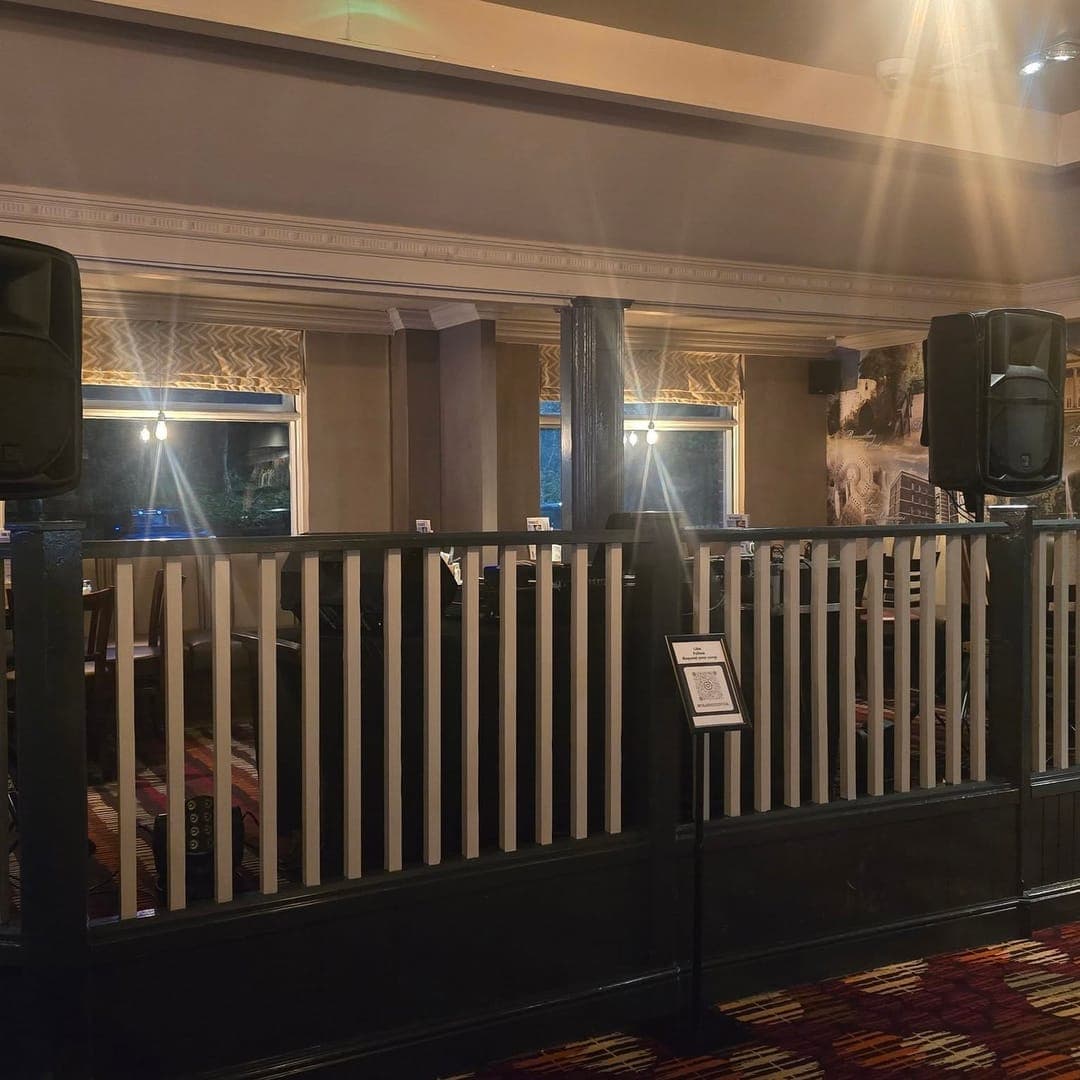 Stage area at The Roundhay pub in Leeds with PA speakers and interior railings ready for live entertainment