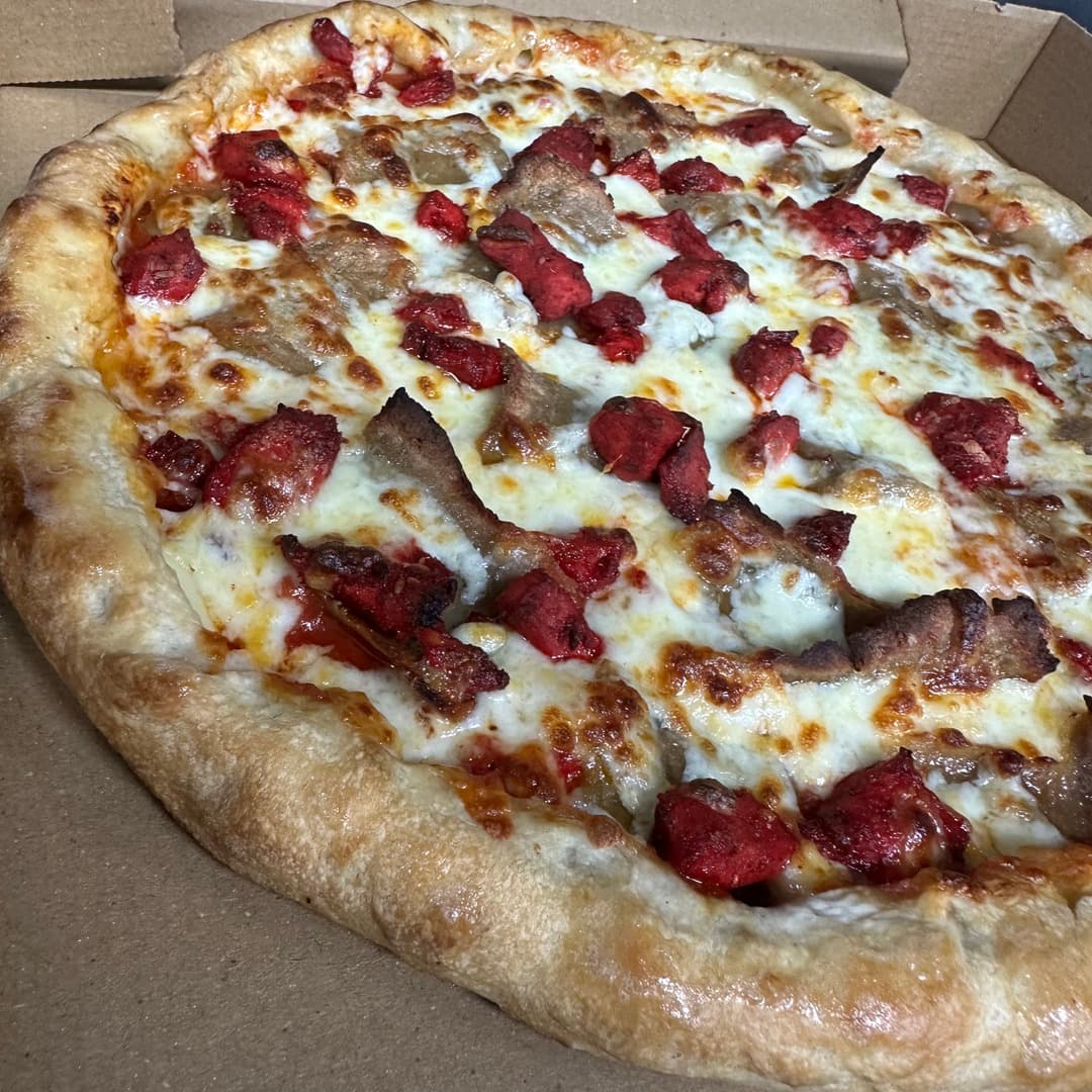 A donner-meat pizza with cheese and chunks of red and brown meat in a takeaway box at Smash Down Leeds.