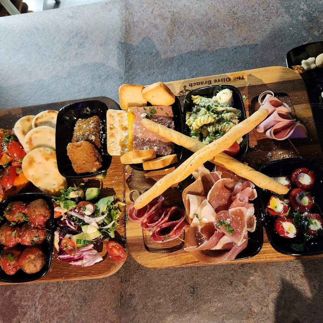Overhead view of two large sharing boards at TAPAS BAR by olive branch loaded with tapas including patatas bravas, charcuterie and croquetas