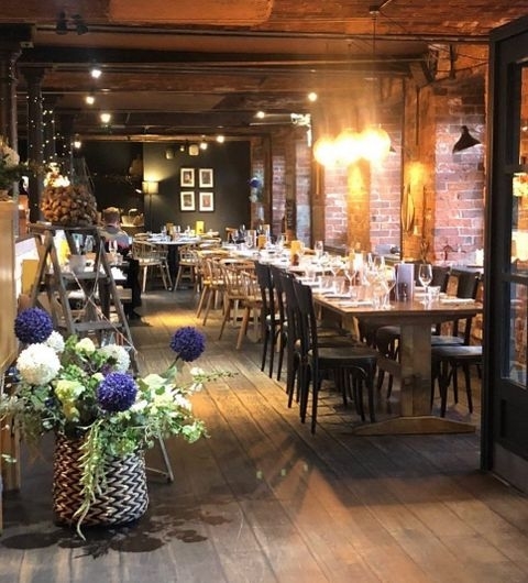 Brasserie_Blanc_Cozy_Interior_Brick_Walls_Wooden_Furniture Interior of Brasserie Blanc with arranged dining tables, exposed brick walls, and warm lighting.