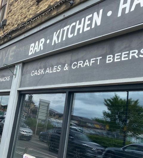 Coopers Bar and Brasserie Ales Beers Signage Exterior view of Coopers Bar and Brasserie showcasing the signage that advertises bar, kitchen, cask ales, and craft beers, with reflections of the street visible in the glass windows.