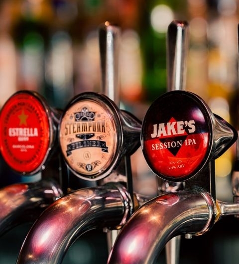 Jakes Bar Still Room Craft Beer Taps Atmosphere Close-up of beer taps at Jake's Bar & Still Room, featuring a variety of beers including Jake's Session IPA.