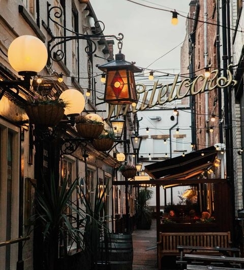 Whitelocks Ale House Evening Ambiance Hanging Lights Street View Charming alleyway view of Whitelock's Ale House with warm lighting, hanging plants, and outdoor seating.