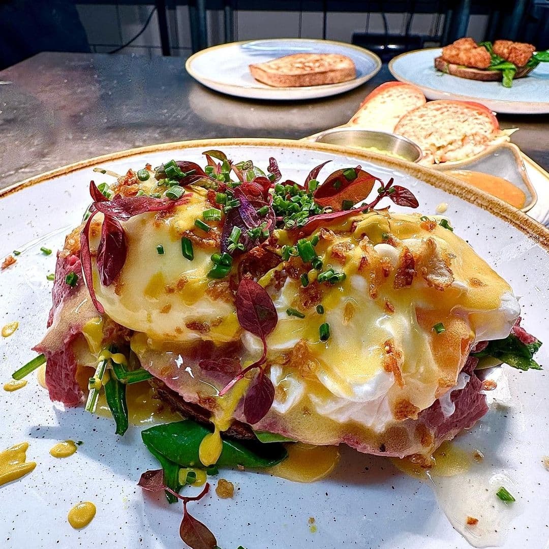 Gourmet eggs benedict with hollandaise sauce and garnishes, served at Olive & Rye.