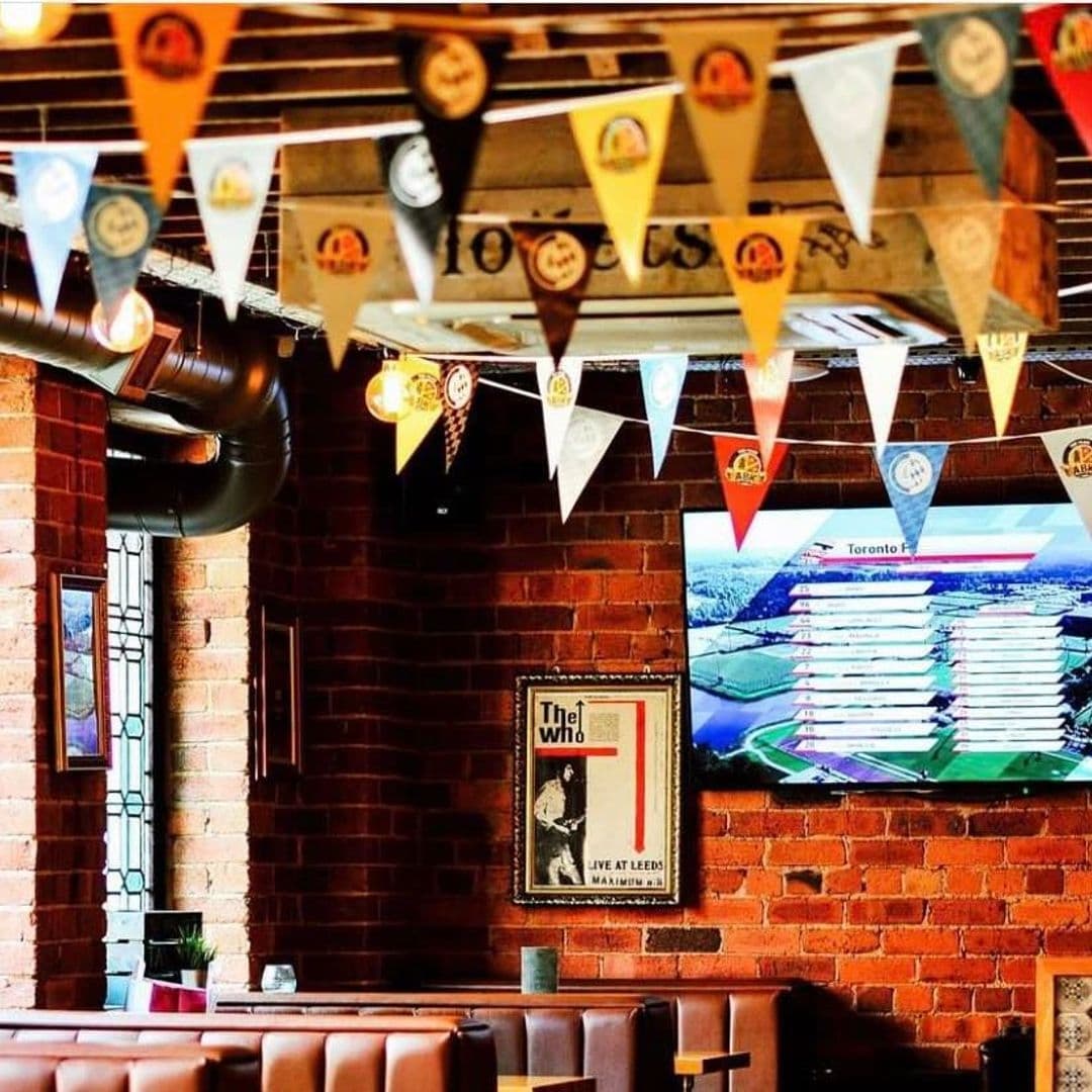 Cozy interior of Parkside Tavern with stringed triangular flags, exposed brick walls, and comfortable seating under warm lighting.