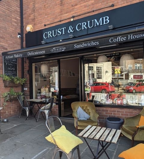 Crust_and_Crumb_Artisan_Bakery_Sidewalk_Cafe Exterior view of Crust & Crumb artisan bakery and coffee house with outdoor seating and open entrance.
