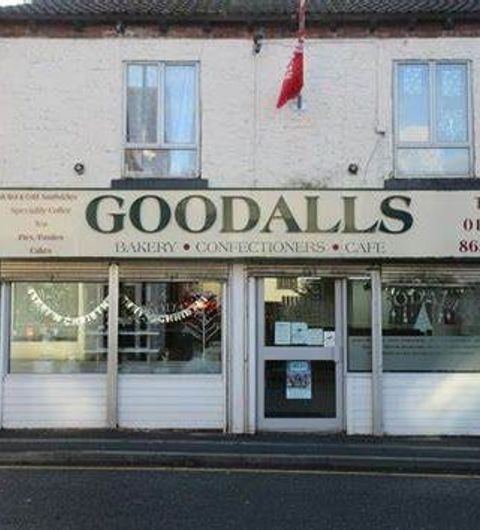 Goodalls Bakery cafe confectionery bakery tourism Front view of Goodalls Bakery, featuring a sign that reads "Goodalls Bakery, Confectioners, Cafe." The building has large windows and a welcoming entrance, with decorative elements visible. A red flag is displayed above the entrance.