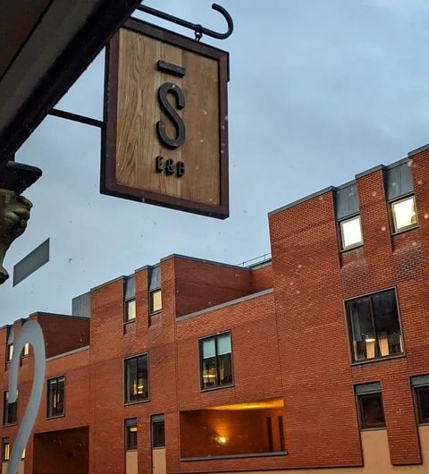 Stage Espresso Brewbar coffee shop sign modern architecture urban view Sign of Stage Espresso & Brewbar hanging outside, with a view of modern brick buildings in the background under a cloudy sky.