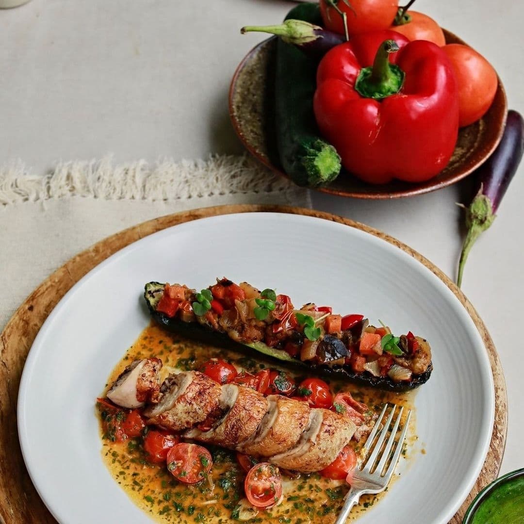 Brasserie Blanc_Gourmet Chicken Dish_Fresh Vegetables_Plating Style Grilled chicken and stuffed zucchini served on a white plate with fresh tomatoes, at Brasserie Blanc.