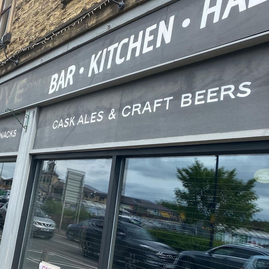 Coopers Bar and Brasserie Facade Cask Ales Craft Beers Exterior view of Coopers Bar and Brasserie showcasing signage that reads "Bar Kitchen" and "Cask Ales & Craft Beers" with reflection of surroundings in the window.