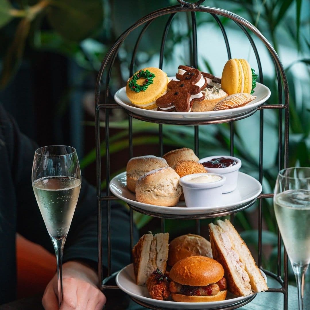 Crafthouse_AfternoonTea_ElegantPresentation_SparklingWine Afternoon tea selection at Crafthouse featuring a three-tiered serving stand with sandwiches, scones, sweet pastries, and a glass of sparkling wine.