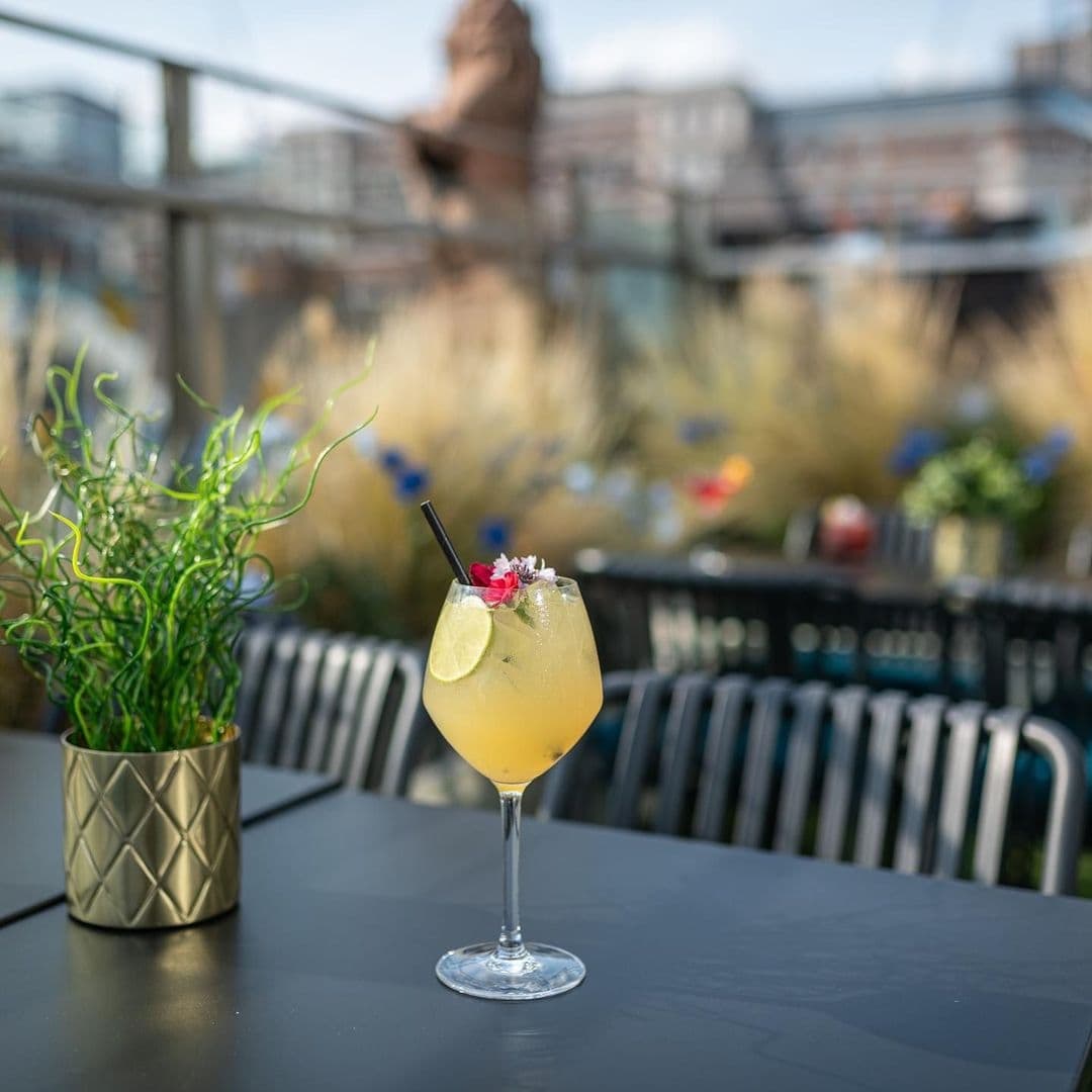 HARVEY NICHOLS Fourth Floor Brasserie Bar Cocktail Outdoor Terrace Refreshing cocktail on the terrace of H A R V E Y • N I C H O L S • Fourth Floor • Brasserie & Bar with urban skyline in the background.