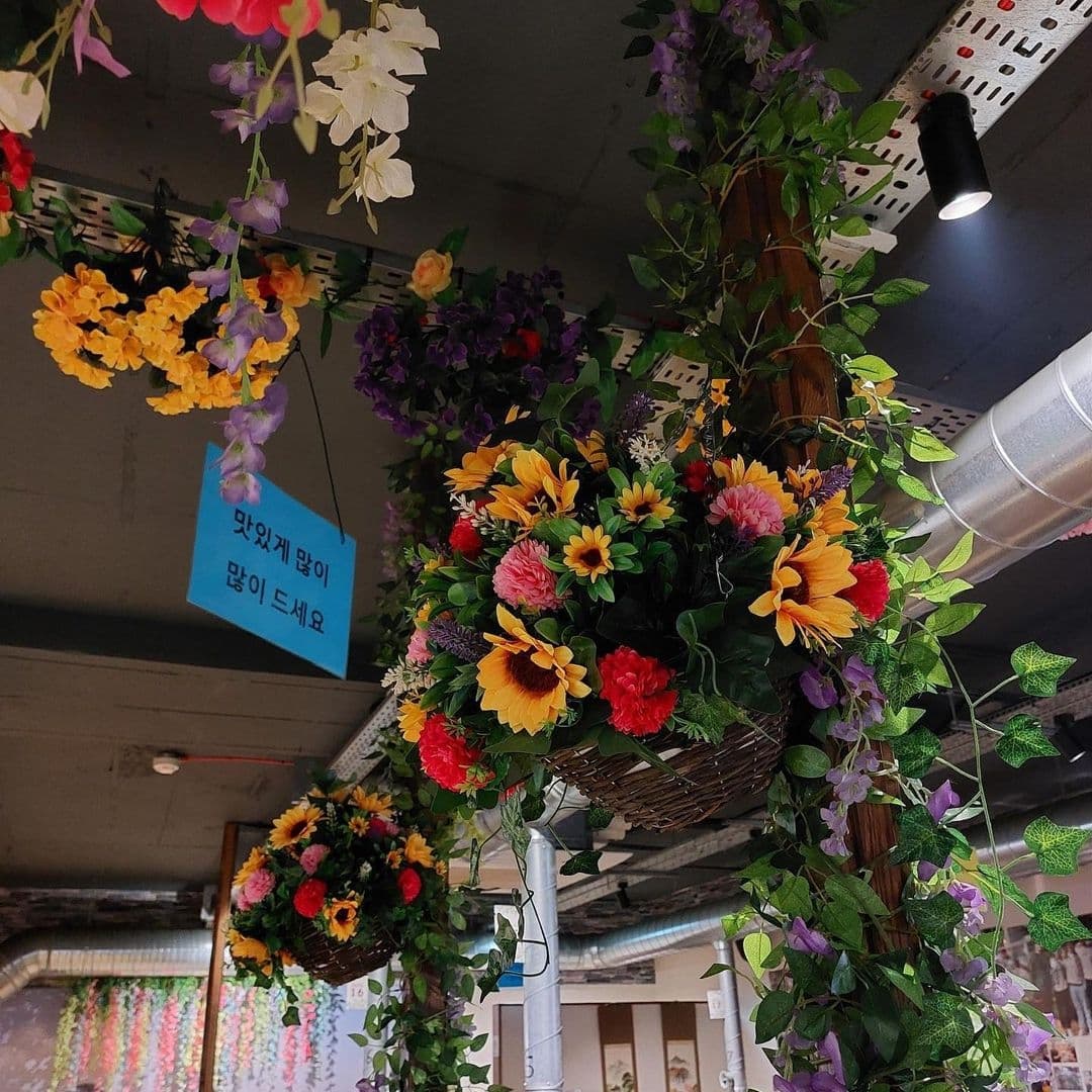 Hama Korean BBQ Buffet Colorful Hanging Flowers Decor Colorful artificial flowers hanging from the ceiling at Hama Korean BBQ Buffet, adding a vibrant and festive atmosphere to the dining experience.