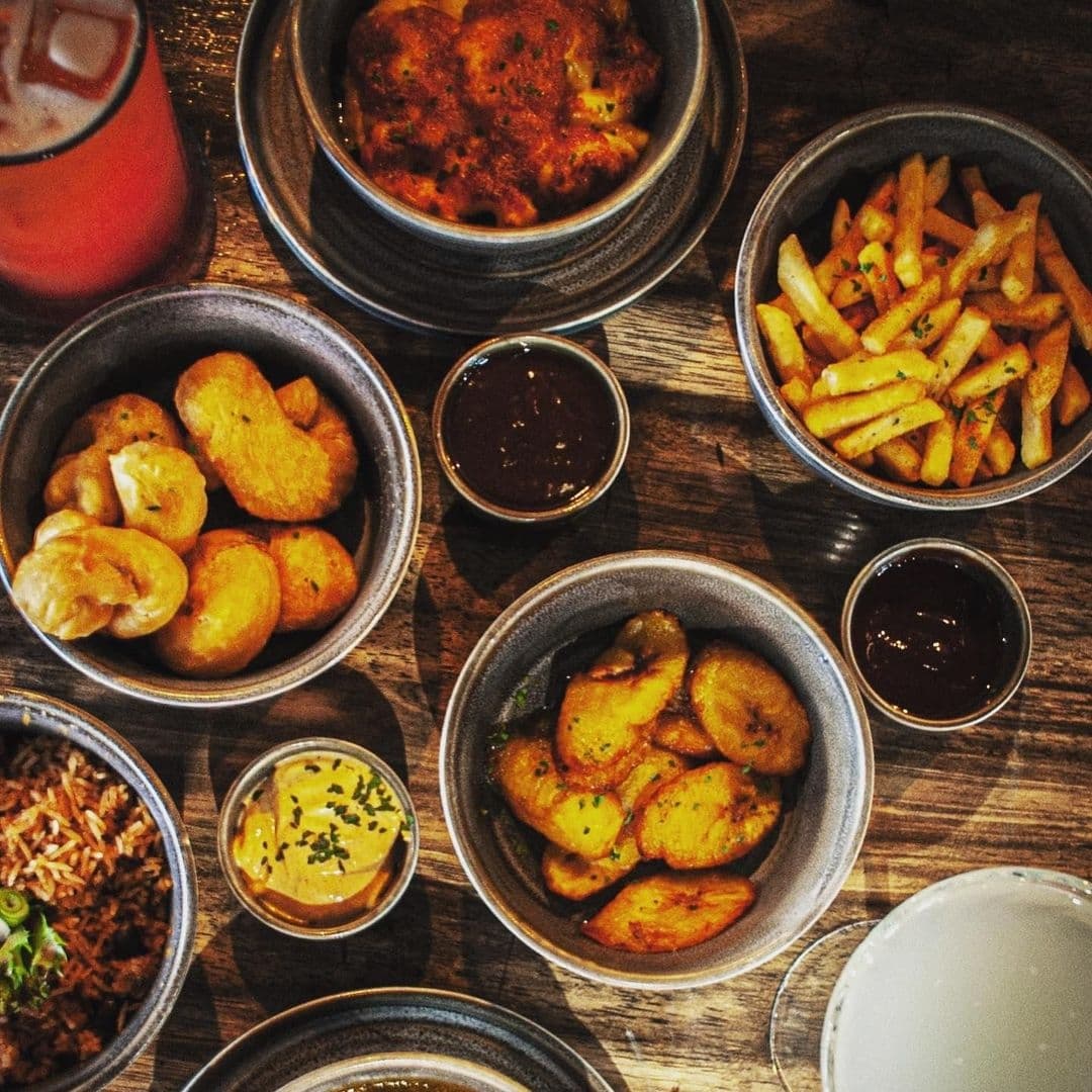 Jamrock Authentic Cuisine Delicious Dishes Local Food Assorted traditional dishes served at Jamrock, featuring fried plantains, seasoned fries, and various dipping sauces.