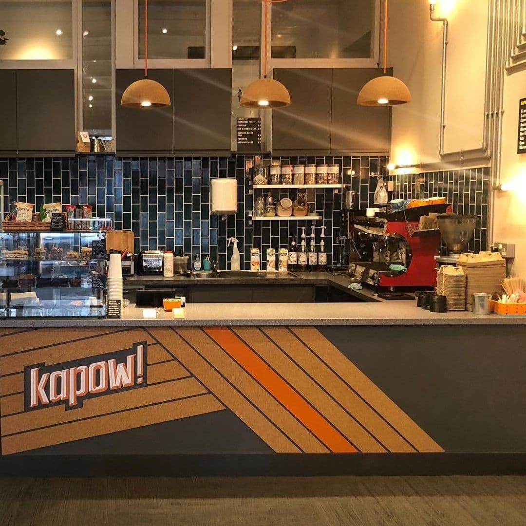 Kapow Coffee The Calls Cosy Interior Espresso Bar Modern Design Interior of Kapow Coffee – The Calls featuring a modern coffee bar with blue tiles, pendant lights, and a prominent 'Kapow!' logo on the front panel.