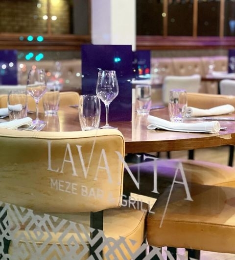 Lavanta Meze Bar Grill Elegant Dining Setup Wine Glasses Interior of Lavanta Meze Bar & Grill with elegantly set tables, wine glasses, and branded chairs in a cozy dining atmosphere.