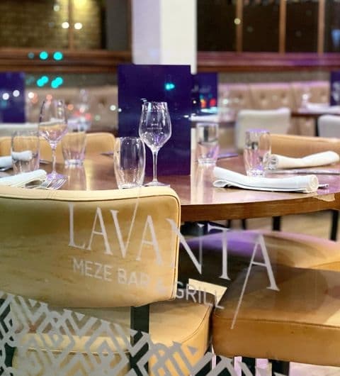 Lavanta Meze Bar Grill Elegant Dining Setup Wine Glasses Interior of Lavanta Meze Bar & Grill with elegantly set tables, wine glasses, and branded chairs in a cozy dining atmosphere.