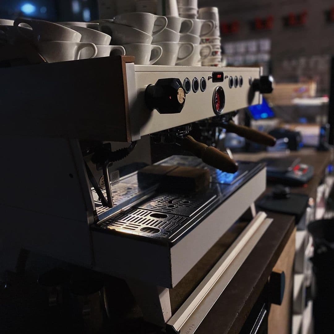 North_Star_Coffee_Shop_Espresso_Machine_Cups_Preparation Professional espresso machine brewing fresh coffee with stacked white cups at North Star Coffee Shop.