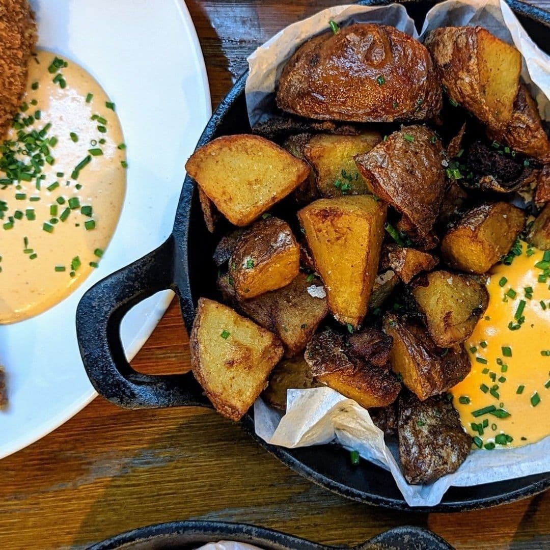 Ox Club at Headrow House Roasted Potatoes Cast Iron Skillet Roasted potatoes served in a skillet garnished with chives at Ox Club at Headrow House.