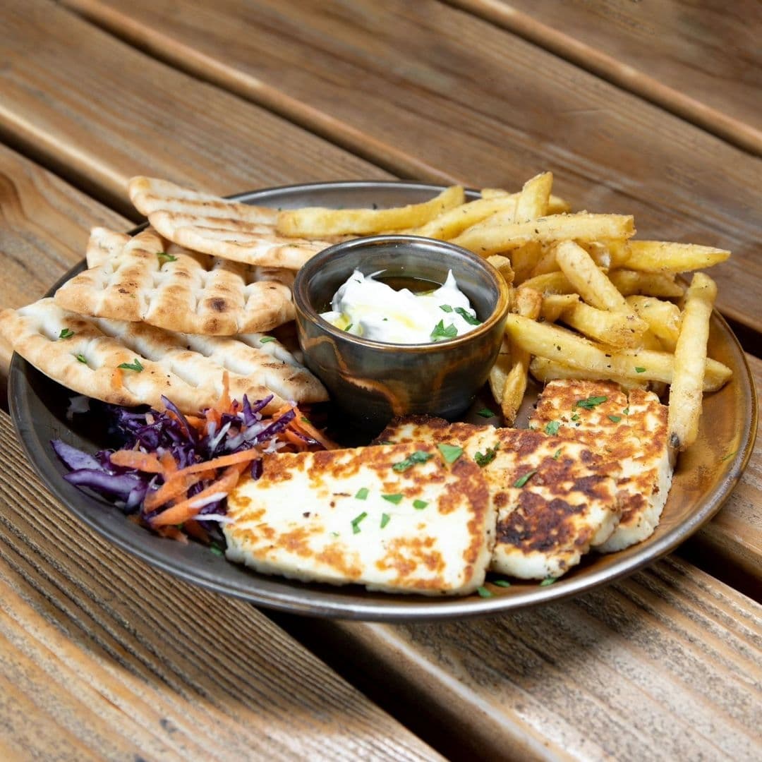 Residence Bar Cafe Kitchen Headingley_Grilled Halloumi Fries Pita Plate Appetizing meal at Residence Bar Cafe | Kitchen (Headingley) featuring grilled halloumi cheese, seasoned fries, pita bread, and a side salad with a dipping sauce.