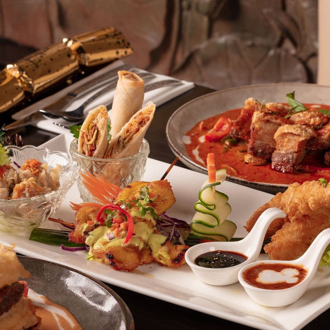 Sukhothai Chapel Allerton Diverse Thai Dishes Platter Assorted Thai dishes served at Sukhothai Chapel Allerton, featuring spring rolls, red curry with meat, fried appetizers with dipping sauces, and a garnished salad.